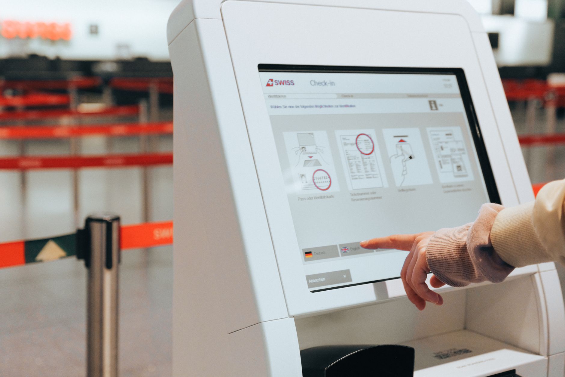 Matkustaja tekee lähtöselvitystä automaatilla passi kädessään lentoasemalla